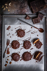 Chocolate cookies lays on white baking paper. Spoon, piece of dark chocolate