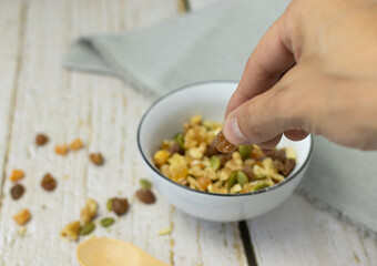 Hand holding raisin over bowl of dried fruit
