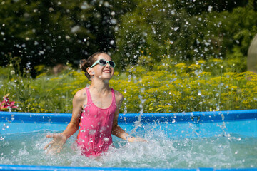 Cheerful teenage girl in sunglasses in the pool playing with water, travel, relax in the hotel