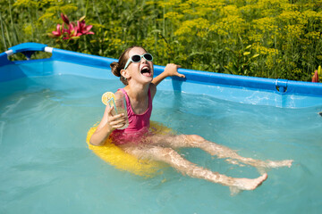 Little cute girl relaxing in swimming pool. Summer travel hotel vacation, swims in the pool and drinks juice