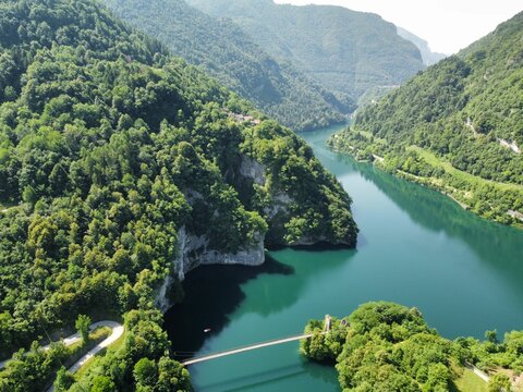 High angle shot of the lake Corlo in a valley surrounded by hills covered with forests