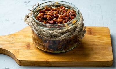Homemade smoked bacon jam in a glass jar close-up.