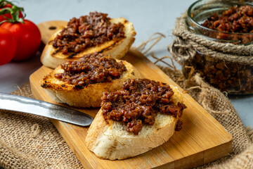 Baguette with spreaded bacon jam, smoked bacon and onion appetizer. Close-up.