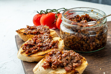 bacon jam in a jar and spread on toasted pieces of baguette. close-up.