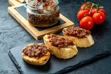 Smoked bacon jam with croutons on a dark background.