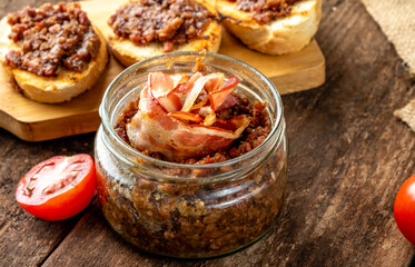 Smoked bacon jam in a glass jar close-up.