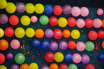 Bunch of multicolored balloons tied for a darts game on a blue wall
