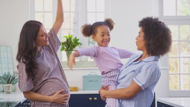 Pregnant Family With Two Mums Wearing Pyjamas Making Morning Pancakes In Kitchen And Dancing With Daughter - Shot In Slow Motion