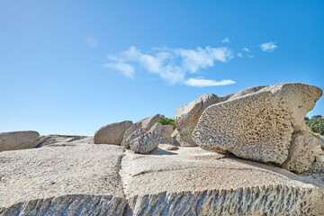 Big boulders on a rocky coast outside on a summer day. Landscape view of a beautiful beach and seashore under a clear blue sky. A natural seaside environment and marine habitat with copy space