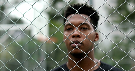 African mixed race man standing behind metal fence