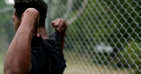African man putting t-shirt on outside and wiping sweat after sport