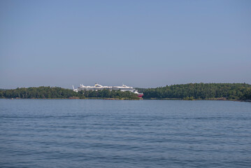 Fototapeta na wymiar Cruise ship visible over an island at an open bay in the archipelago a sunny summer day in Stockholm