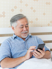 Senior Male , Asian old man using a smartphone feel happy good health on bed at home - lifestyle senior concept
