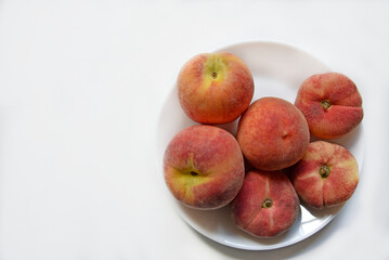 Naklejka na ściany i meble Juicy red and yellow peaches on a white plate. Delicious peaches for lunch.
