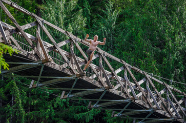 An athletic adventurous male jumping off a high bridge into a river.