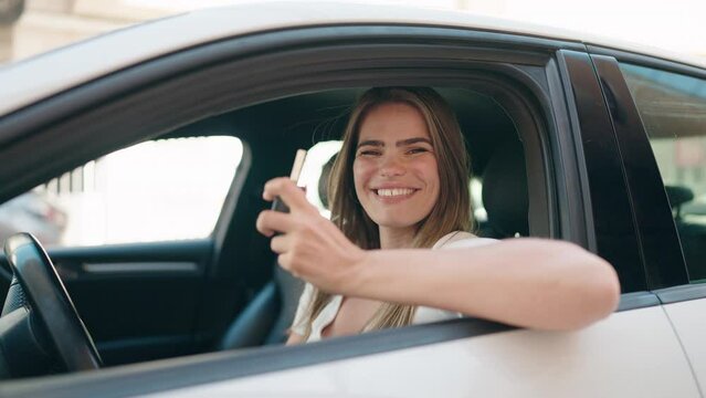 Young woman smiling confident holding key of new car at street