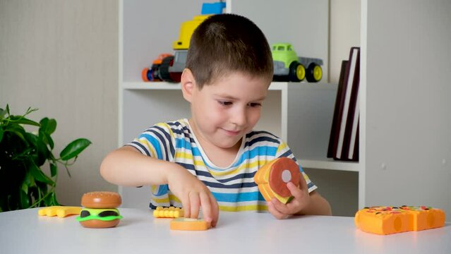 A 5-year-old boy plays with plastic food - sandwiches and burgers with Velcro.