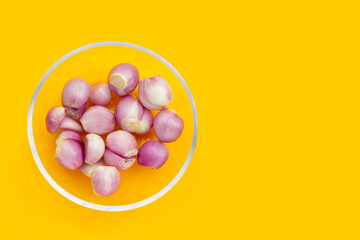 Fresh shallot in glass bowl on yellow background
