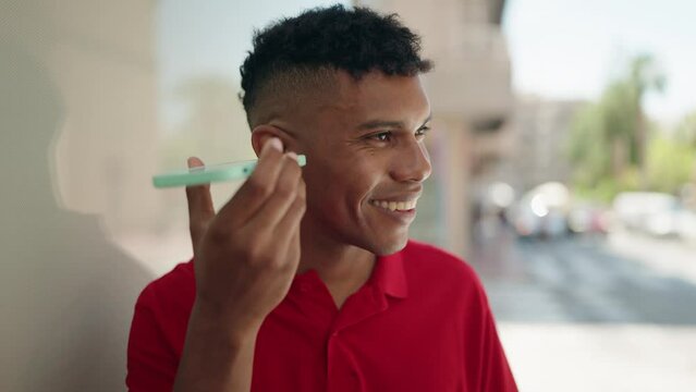Young latin man smiling confident listening audio message by the smartphone at street