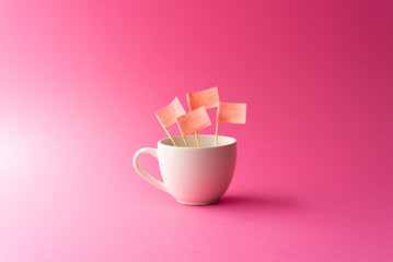 Cup with pink paper flags inside and pink or fuchsia background
