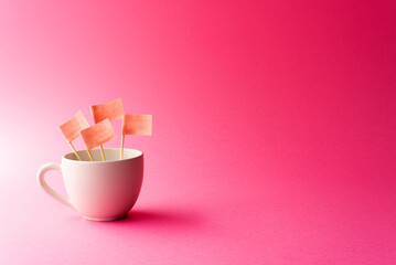 Cup with pink paper flags inside and pink or fuchsia background
