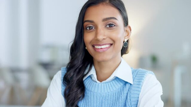 Confident and happy indian business woman feeling ambitious and motivated for success in a creative startup agency. Portrait of a young designer smiling while working on a laptop in a modern office.