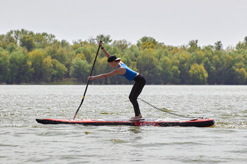 Young sporty attractive woman on Stand Up Paddle Board, SUP, paddle in the river