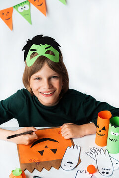 A boy in a Hulk mask draws with an orange felt-tip pen. Halloween party