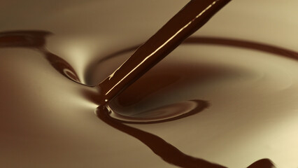 Close-up of stirring stream of melted chocolate.