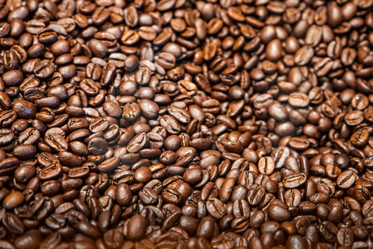 A large bin or pile of whole brown organnic coffee beans