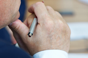 A fountain pen in the hands of a thoughtful adult man. Anonymous, unrecognizable. Selective focus.