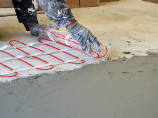 a worker unfolds a roll of warm electric floor for laying under a cement screed