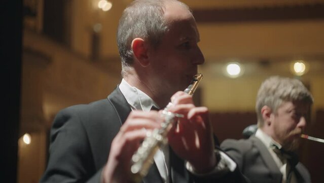 flutists is playing music in orchestra, musical band on scene of theater, two professional musicians