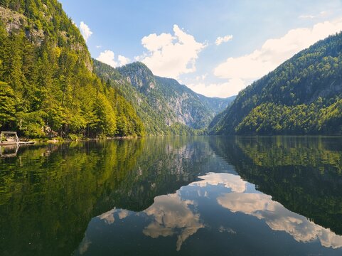 Mesmerizing landscape of the lake Tolitz with forested mountains and cloudy sky reflected in water