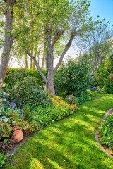 Vibrant garden setting with flowers, plants and a lush lawn with green grass. Beautiful sunny...