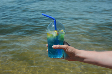 refreshing cocktail with a straw. sea, sun, sandy beach. summer vacation. a cool drink. background for the design.