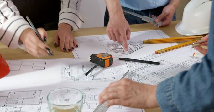 Hands of architects with construction project design drawings sketches. Brainstorming of construction engineers over a work table with blueprints.