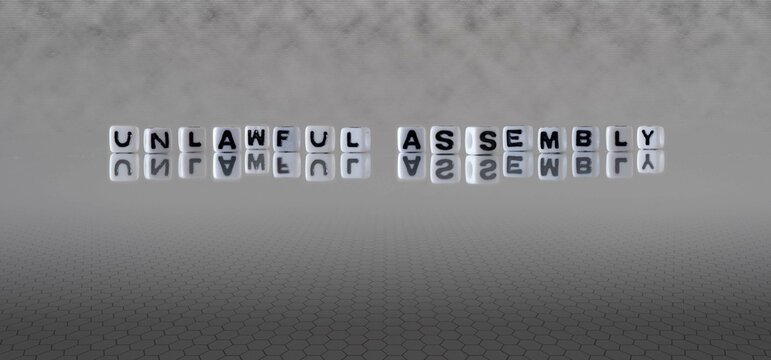 Unlawful Assembly Word Or Concept Represented By Black And White Letter Cubes On A Grey Horizon Background Stretching To Infinity