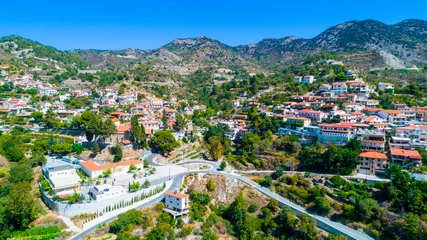 Schilderijen op glas Aerial view of Agros village settlement on mountain Troodos, Limassol district, Cyprus. Bird's eye view of traditional houses with ceramic tile roof, church, countryside and rural landscape from above © f8grapher