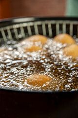 Deep frying brazilian croquettes stuffed with chiken in boiling soybean oil. Coxinha de frango.