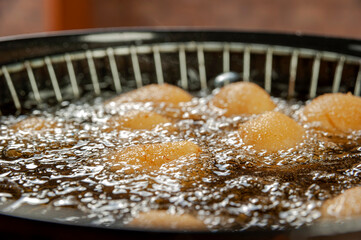 Deep frying brazilian croquettes stuffed with chiken in boiling soybean oil. Coxinha de frango.