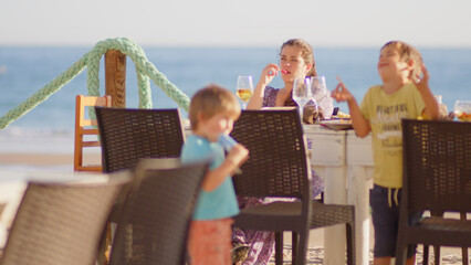 4 sibling boys look at the camera smiling, play while running through a restaurant in front of the camera, eat ice cream, hug their mother