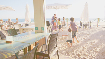 4 sibling boys look at the camera smiling, play while running through a restaurant in front of the camera, eat ice cream, hug their mother