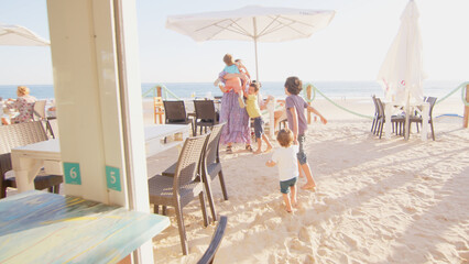 4 sibling boys look at the camera smiling, play while running through a restaurant in front of the camera, eat ice cream, hug their mother