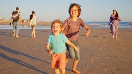 Wonderful family - father, mother and 4 sons (1-8 years old) - walk along one of the most beautiful beaches of Cádiz at sunset - they love and hug each other, look after their children