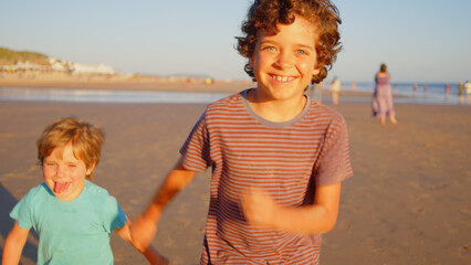 Wonderful family - father, mother and 4 sons (1-8 years old) - walk along one of the most beautiful beaches of Cádiz at sunset - they love and hug each other, look after their children