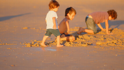 Wonderful family - father, mother and 4 sons (1-8 years old) - walk along one of the most beautiful beaches of Cádiz at sunset - they love and hug each other, look after their children