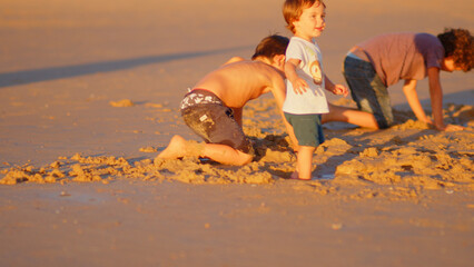 Wonderful family - father, mother and 4 sons (1-8 years old) - walk along one of the most beautiful beaches of Cádiz at sunset - they love and hug each other, look after their children