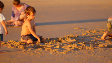 Wonderful family - father, mother and 4 sons (1-8 years old) - walk along one of the most beautiful beaches of Cádiz at sunset - they love and hug each other, look after their children