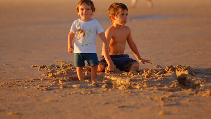 Wonderful family - father, mother and 4 sons (1-8 years old) - walk along one of the most beautiful beaches of Cádiz at sunset - they love and hug each other, look after their children